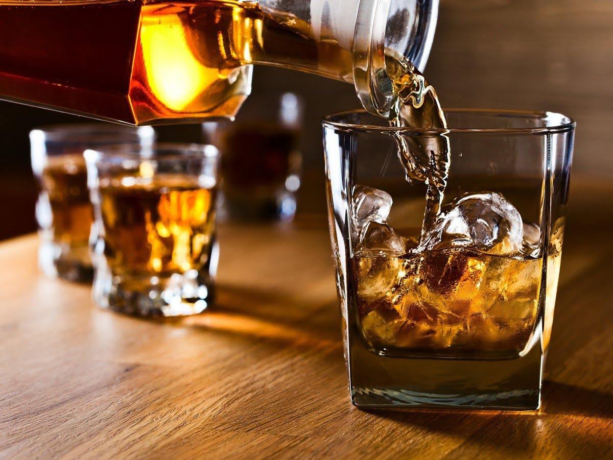 Наливание виски в стакан со льдом